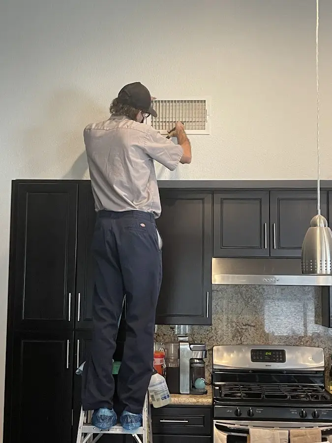 Technician inspecting an air vent during HVAC service in Santa Fe
